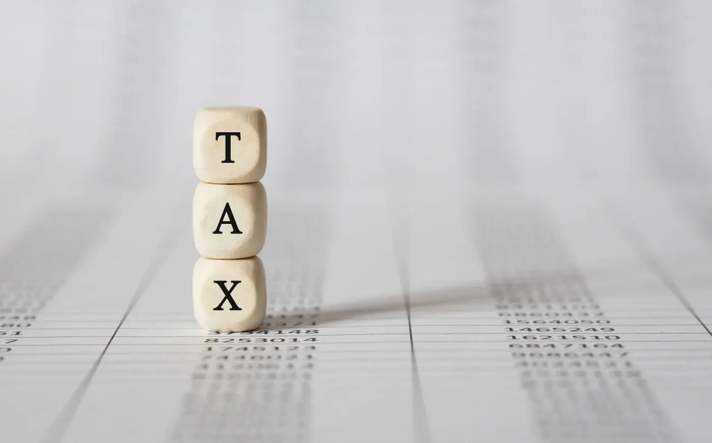Wooden blocks spelling tax, standing on a printed worksheet.